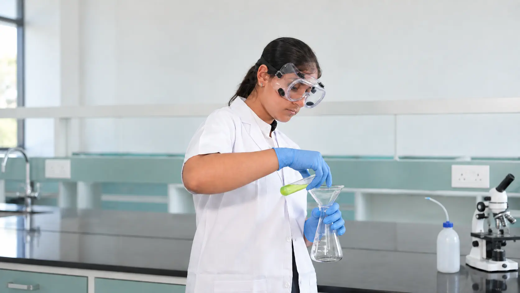 ABODE student conducting a science experiment with protective goggles and gloves
